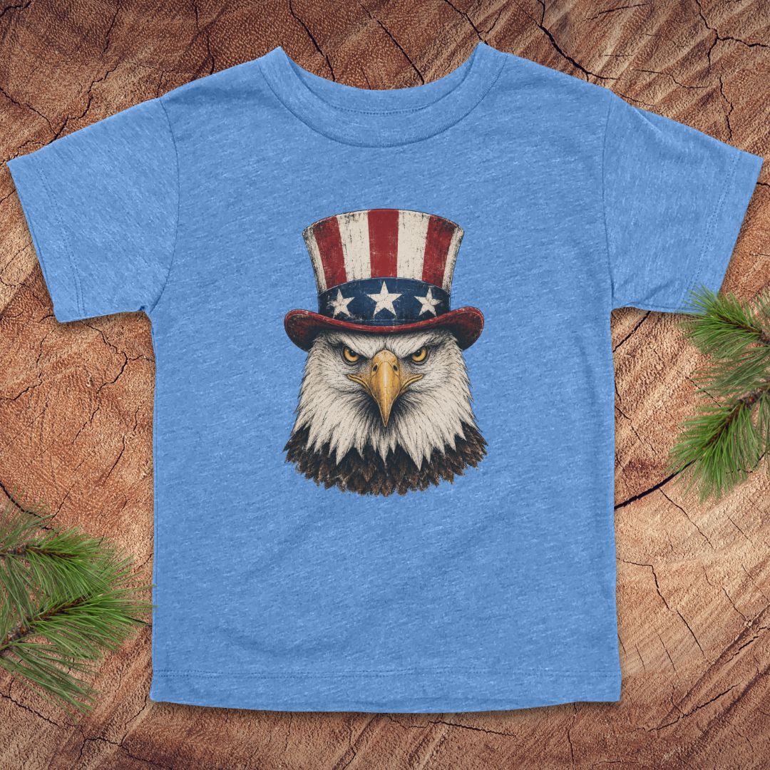 Blue t-shirt with an eagle wearing a top hat on a wooden surface