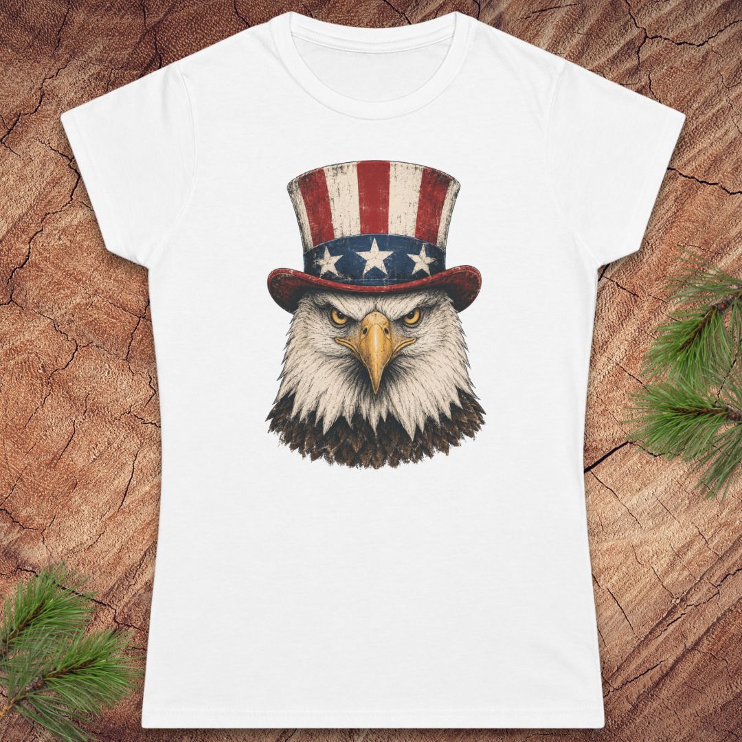 White t-shirt with an eagle wearing an American flag hat on a wooden surface.