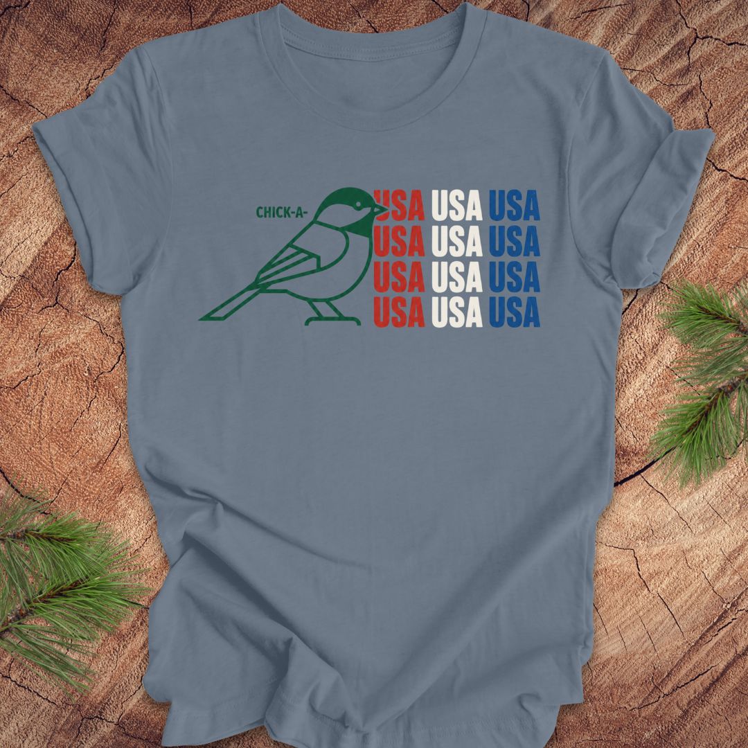 Blue t-shirt with a chickadee bird graphic and 'USA' text on a wooden surface.