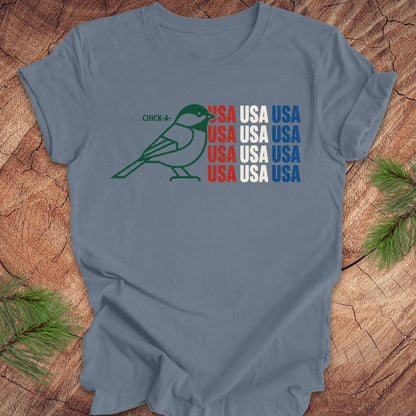 Blue t-shirt with a chickadee bird graphic and 'USA' text on a wooden surface.
