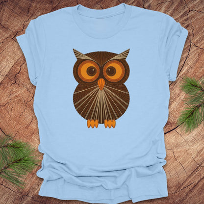 Baby blue colored t-shirt with a vintage owl design on a wooden surface