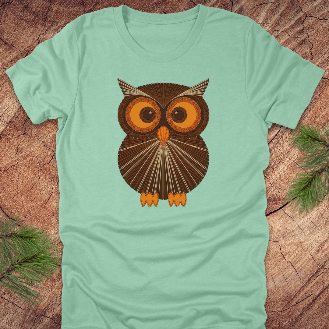 Mint green colored t-shirt with a vintage owl design on a wooden surface