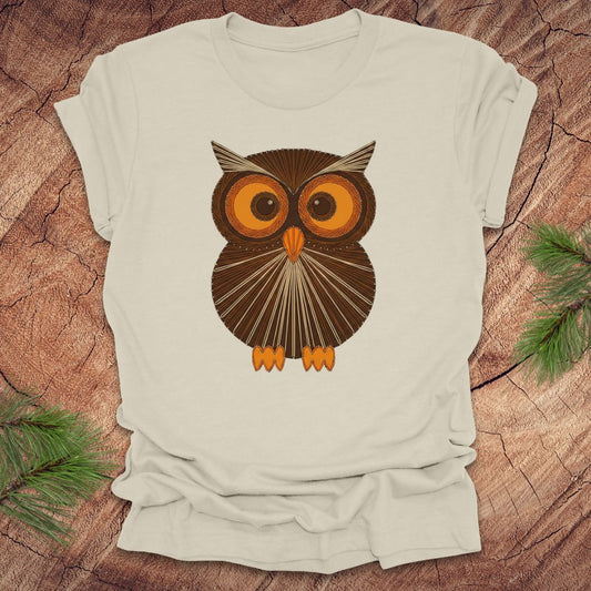 Beige colored t-shirt with a vintage owl design on a wooden surface