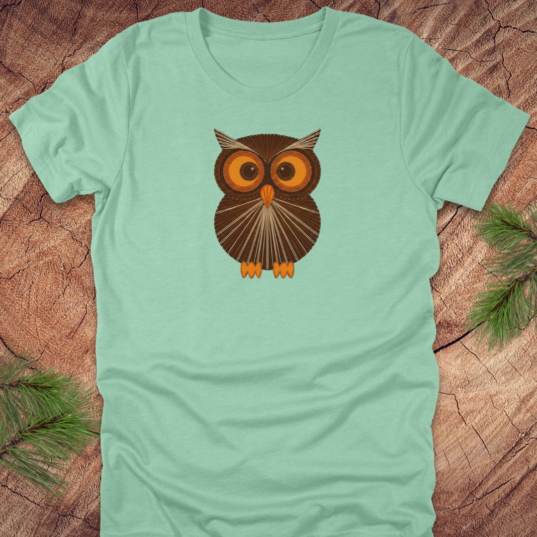 Mint green t-shirt with a vintage string art owl in browns and oranges on a wood background.