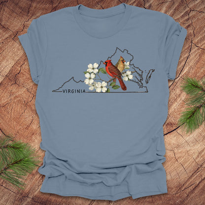 Blue t-shirt with a Virginia map and cardinal design on a wooden surface