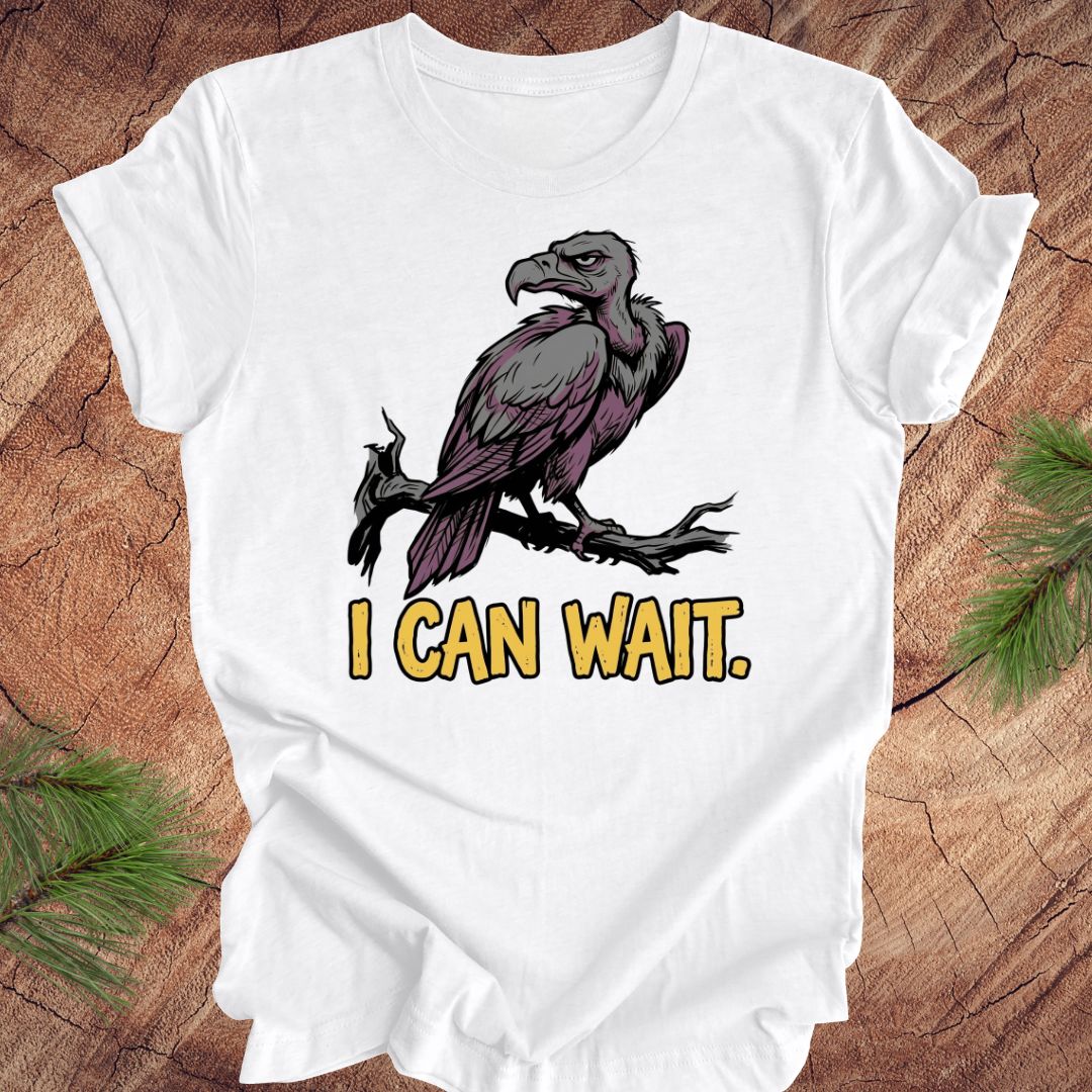 White t-shirt with a vulture graphic and 'I CAN WAIT.' text on a wooden surface.