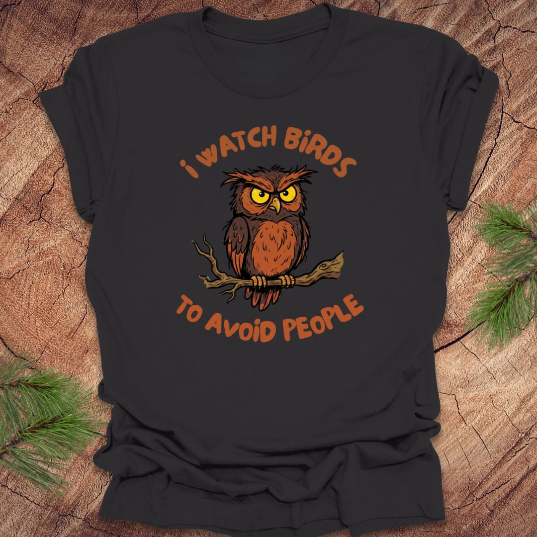 Dark gray t-shirt with an owl graphic and text, 'I watch birds to avoid people' on a wooden background