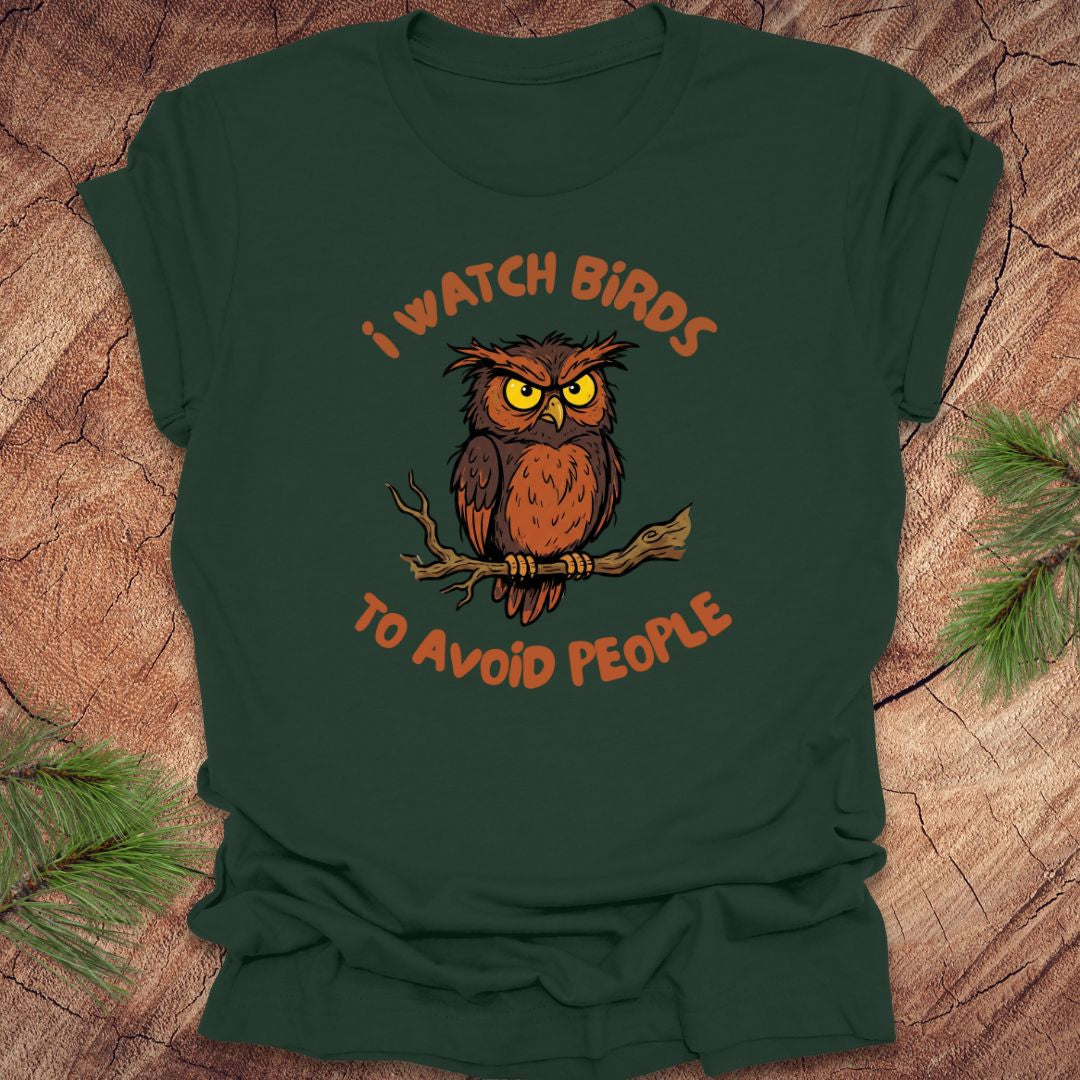 Dark green t-shirt with an owl graphic and text, 'I watch birds to avoid people' on a wooden background