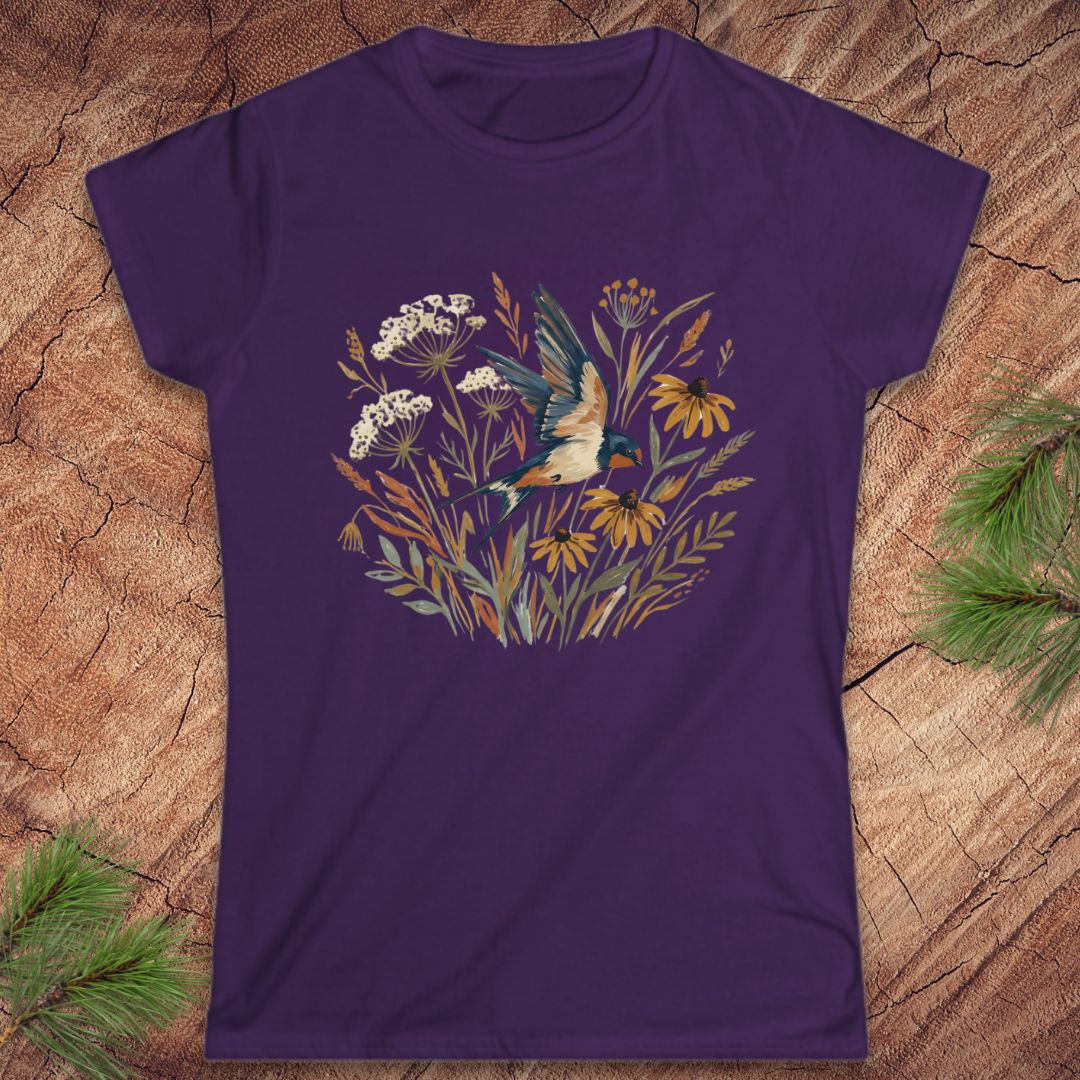 Purple t-shirt with nature-themed design featuring a bird and flowers on a wooden surface.
