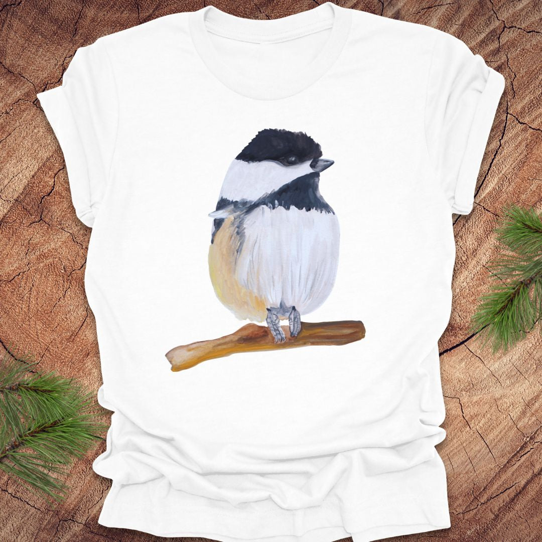 White t-shirt with a watercolor chickadee on a wooden surface