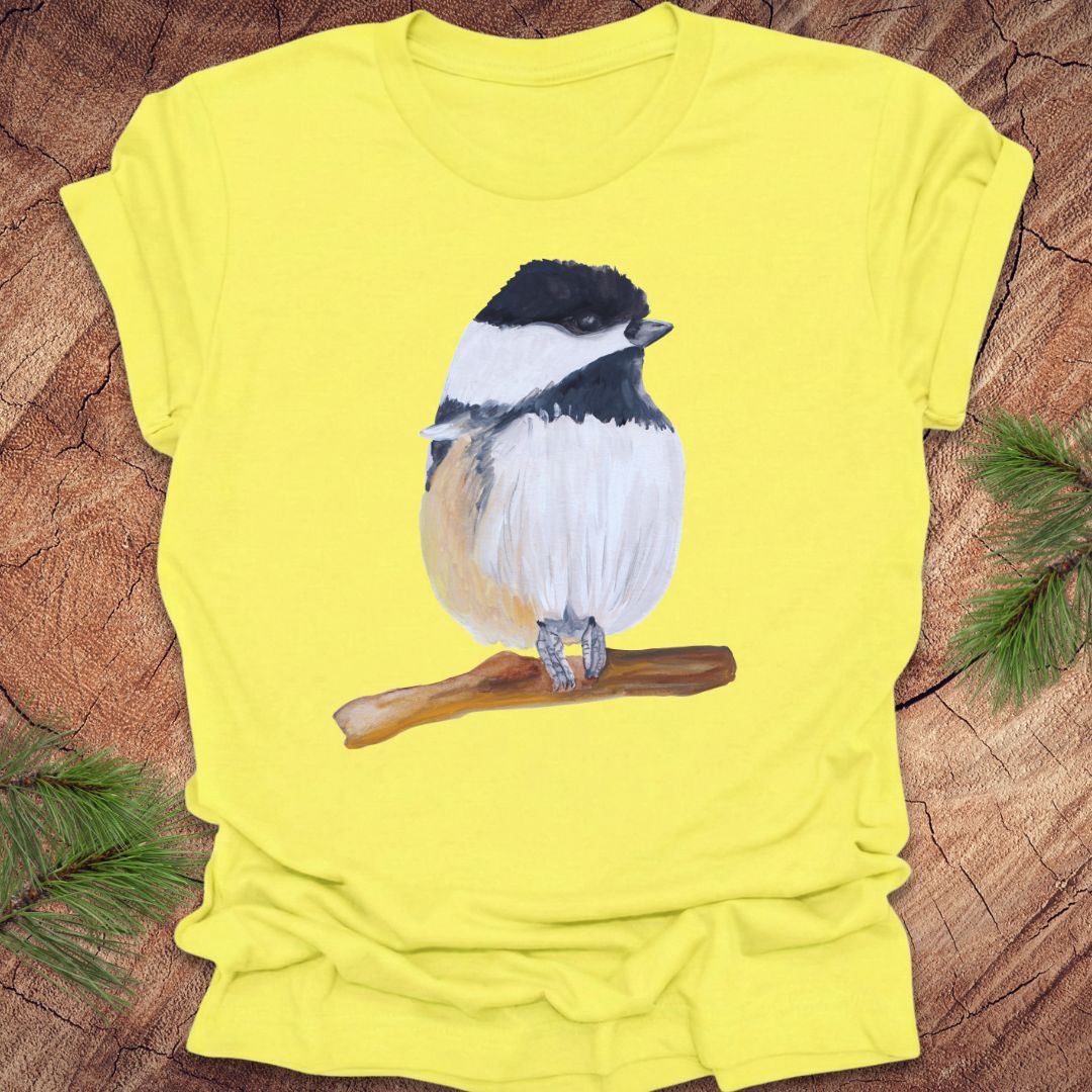 Yellow t-shirt with a watercolor chickadee on a wooden surface