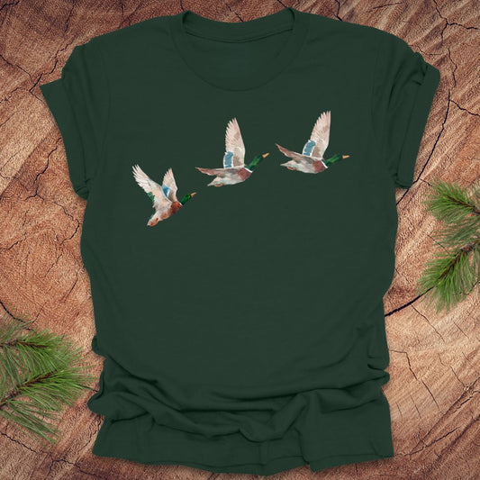 Dark green t-shirt with three flying watercolor mallard duck designs on a wooden surface.