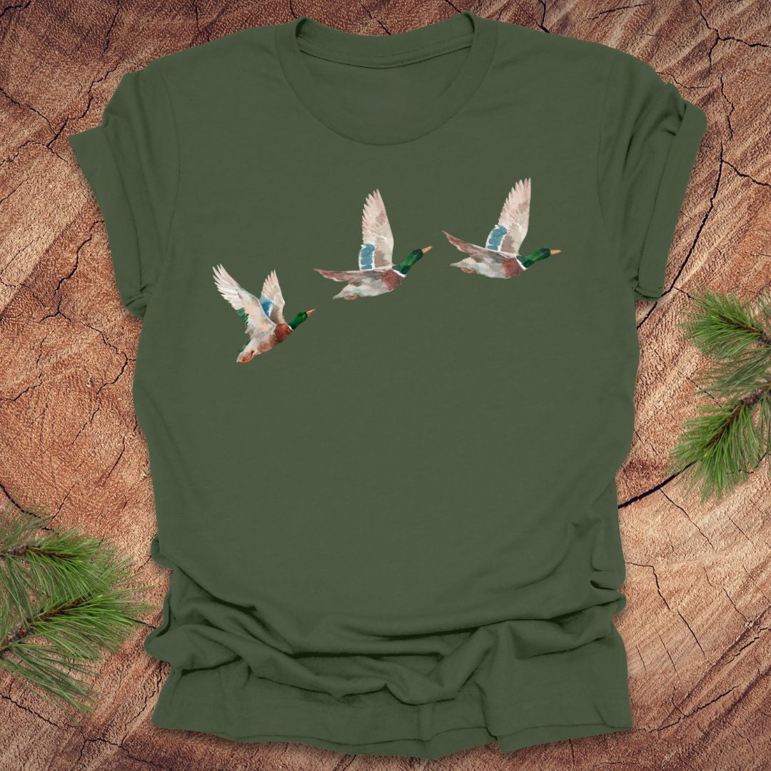 Mililtary green t-shirt with three flying watercolor mallard duck designs on a wooden surface.