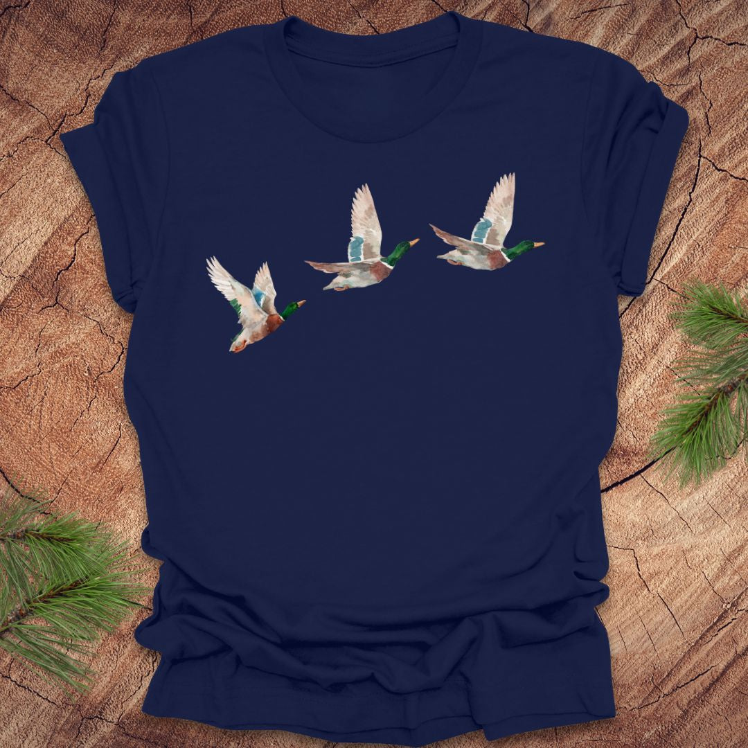Navy blue t-shirt with three flying watercolor mallard duck designs on a wooden surface.