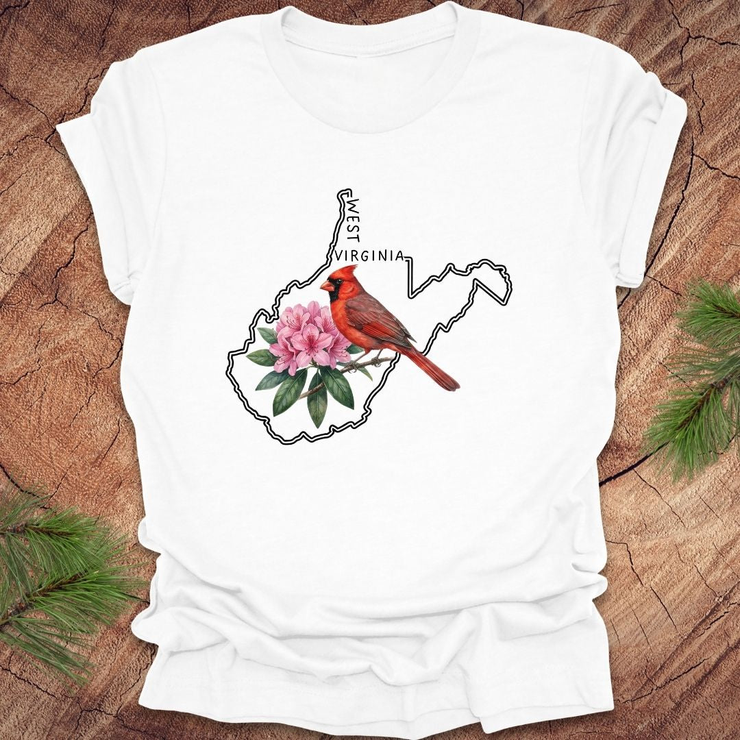 White t-shirt with the outline of West Virginia and its state bird,and flower cardinal and  rhododendron, on a wooden background.