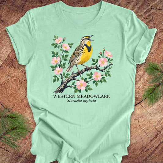 Light green t-shirt with a Western Meadowlark graphic on a wooden surface