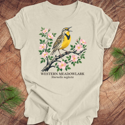 Beige t-shirt with a Western Meadowlark graphic on a wooden surface