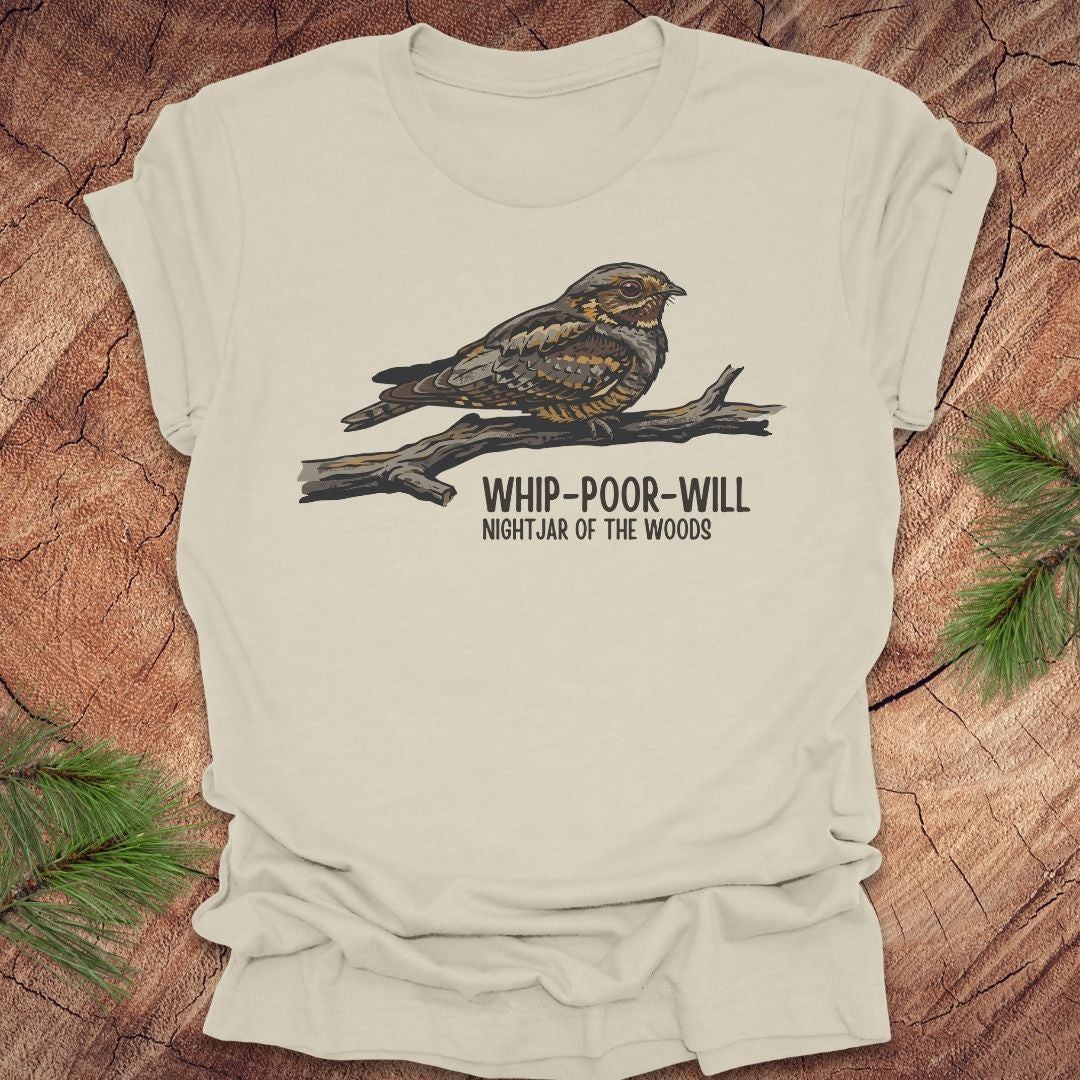 Beige t-shirt with a whip-poor-will bird on a branch with text 'nightjar of the woods' on a wood background.