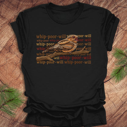 Black t-shirt with a bird graphic and 'whip-poor-will' text on a wooden surface.