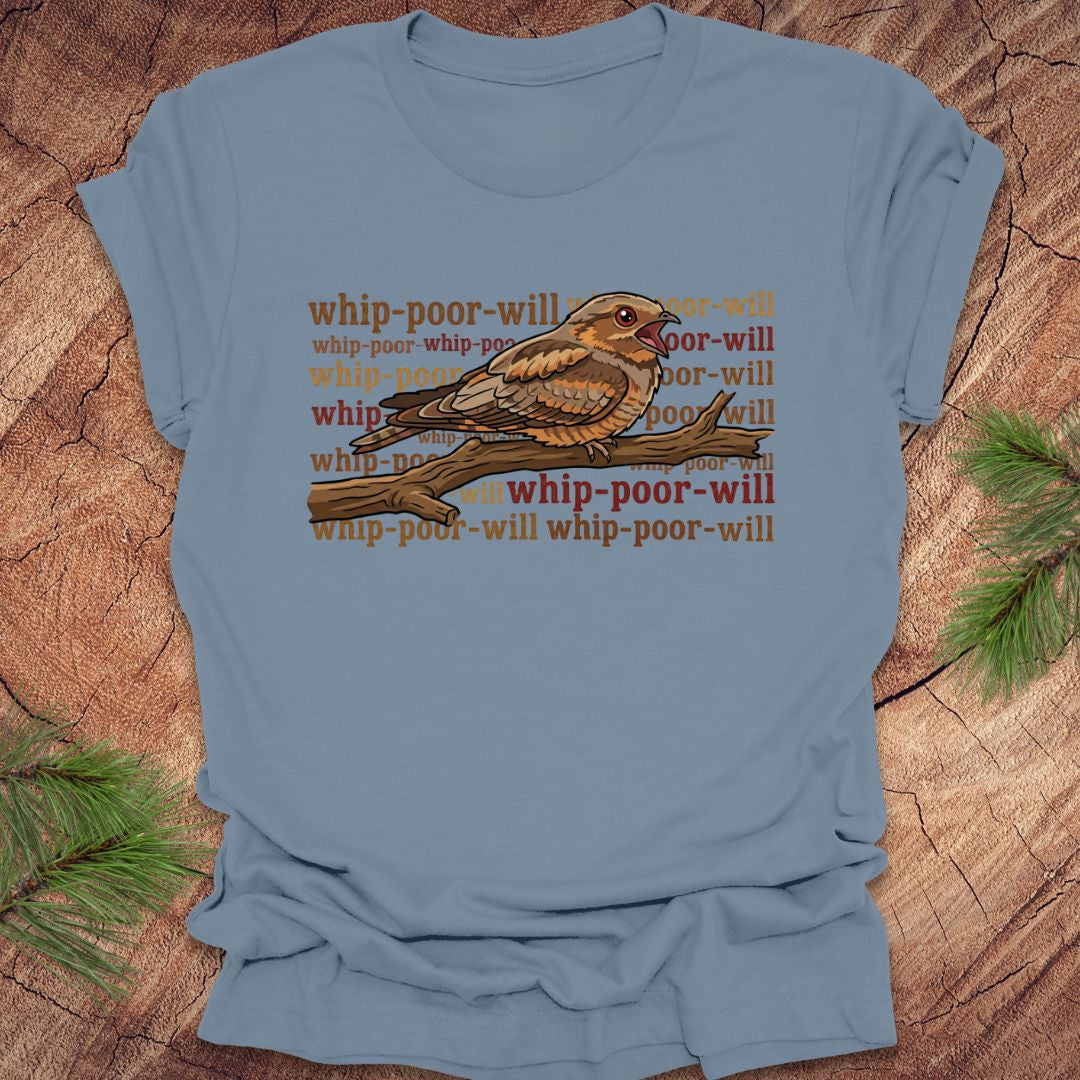 Blue t-shirt with a bird graphic and 'whip-poor-will' text on a wooden surface.