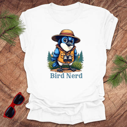 White t-shirt with an animated blue jay in birdwatching gear with "bird nerd" text on a wood background.