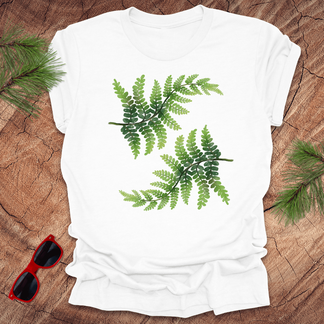 White t-shirt with green leaf design on a wooden surface with sunglasses and leaves.