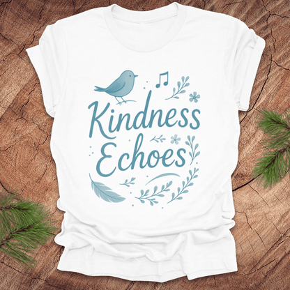 White t-shirt with birds and flowers and text, 'Kindness Echoes' design on a wooden surface.