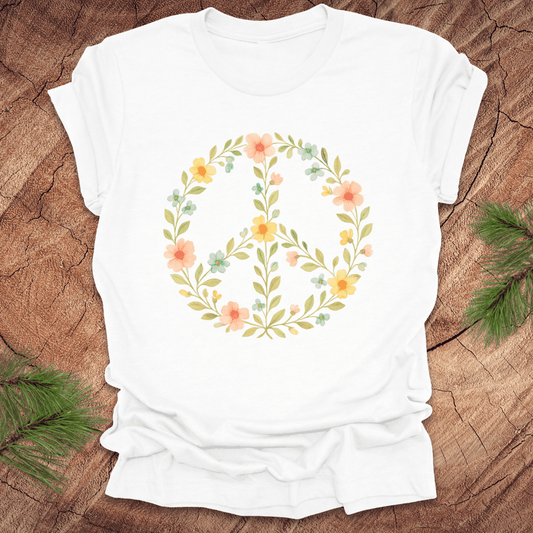 White t-shirt with a peace sign made of flowers on a wood background.