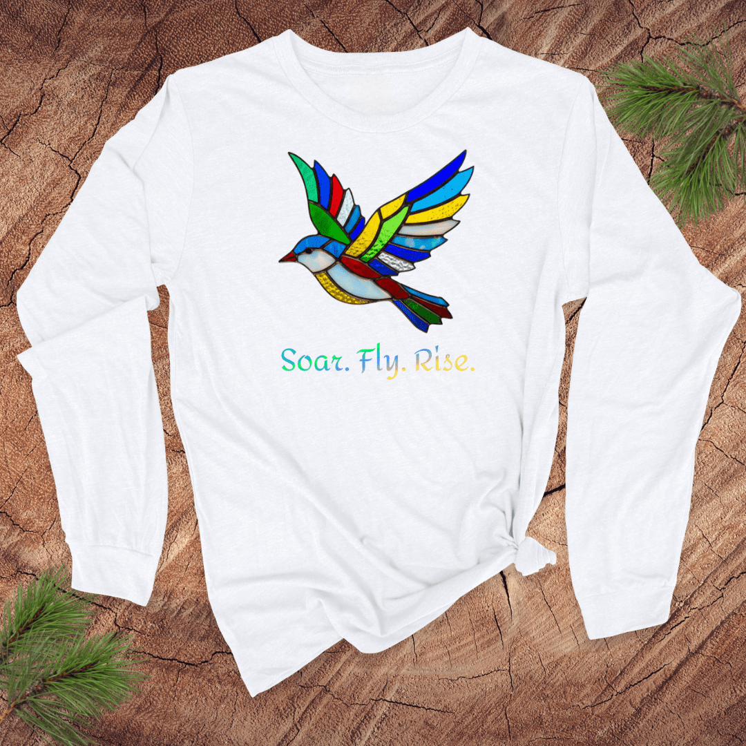 White long sleeve tshirt with a colorful bird design and 'Soar. Fly. Rise.' text on a textured brown background.