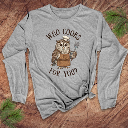 Gray long-sleeve shirt with an owl graphic and text 'who cooks for you' on a wooden surface