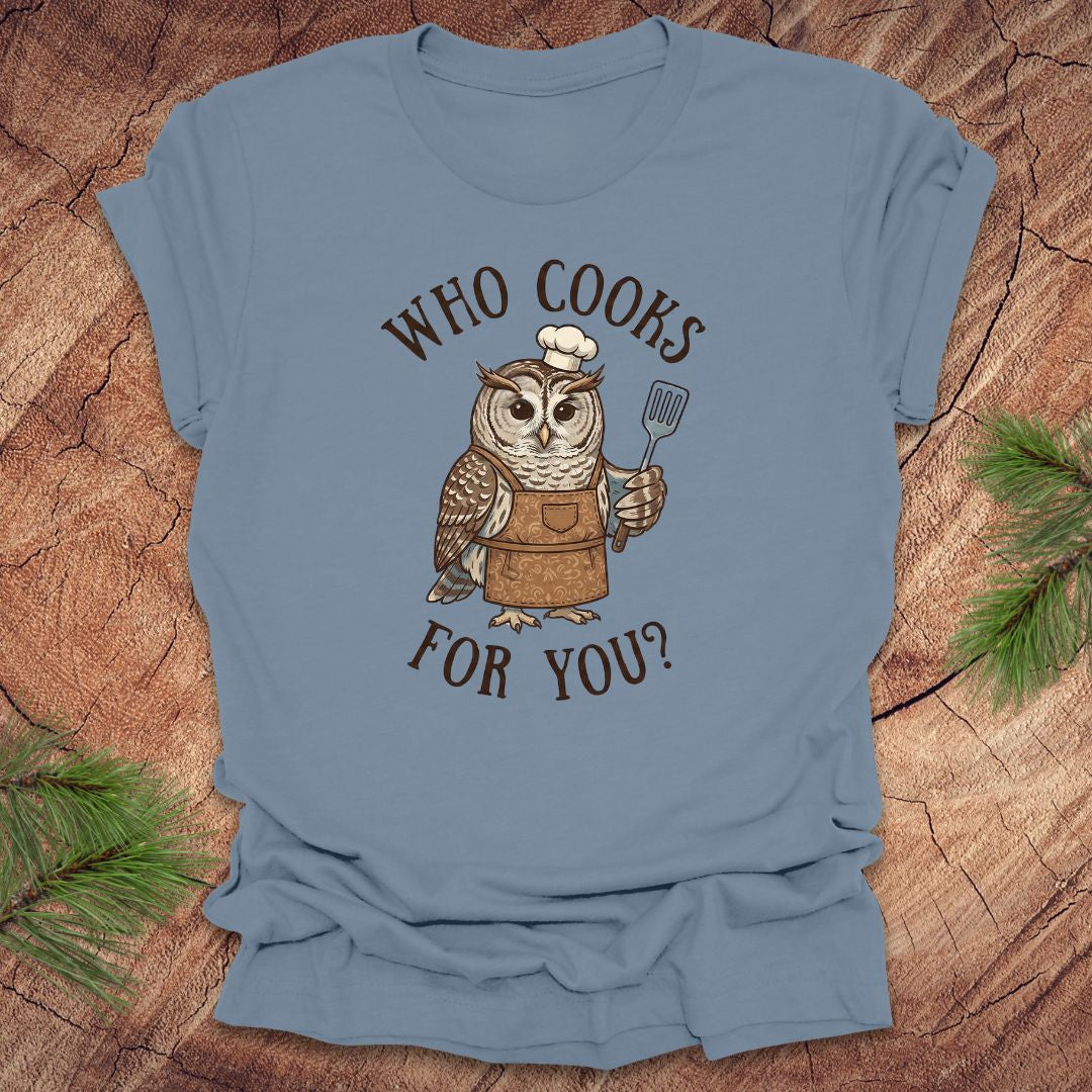 Steel blue t-shirt with an owl graphic and text 'who cooks for you' on a wooden surface