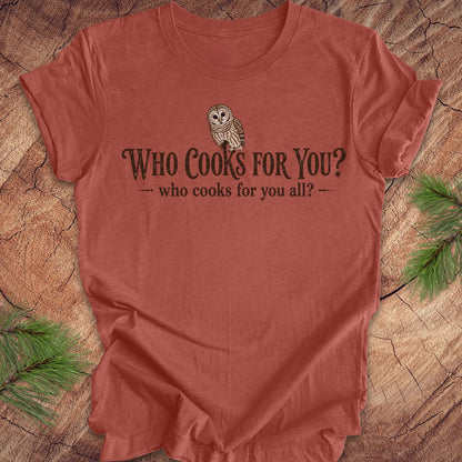Red t-shirt with owl graphic and text on a wooden surface