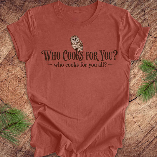 Red t-shirt with owl graphic and text on a wooden surface