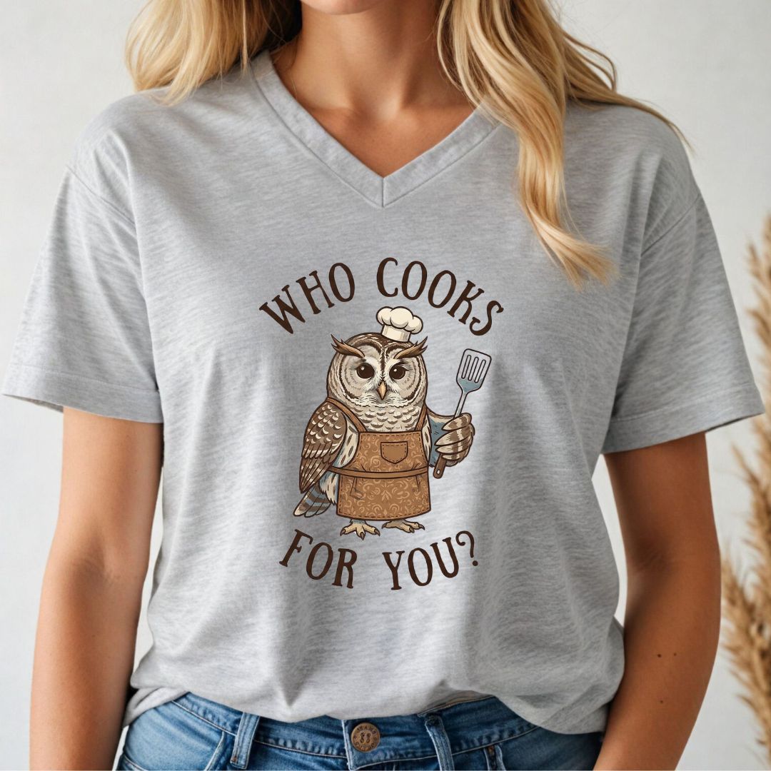 Person wearing a gray v-neck t-shirt with an owl graphic and text 'WHO COOKS FOR YOU?'