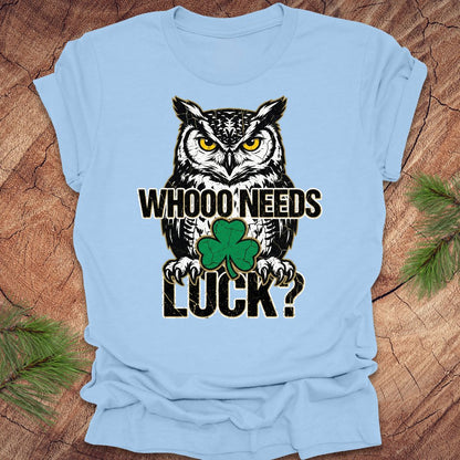 Baby blue t-shirt with an owl st patrick's day graphic and text 'WHOO NEEDS LUCK?' on a wooden surface.