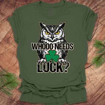 Green t-shirt with an owl st patrick's day graphic and text 'WHOO NEEDS LUCK?' on a wooden surface.