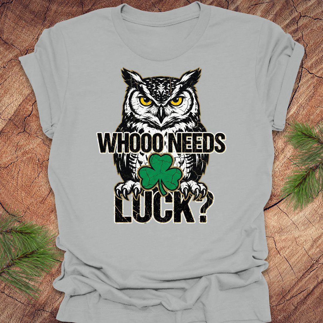 Gray t-shirt with an owl st patrick's day graphic and text 'WHOO NEEDS LUCK?' on a wooden surface.