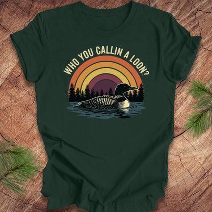 Green t-shirt with a loon graphic and text 'who you callin a loon' on a wooden surface