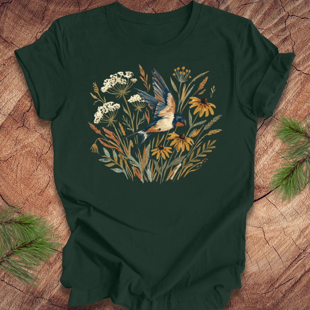 Dark green t-shirt with watercolor flowers and a barn swallow in flight, on a wood background. 