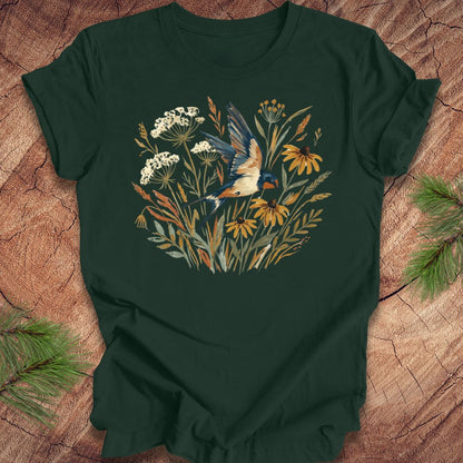 Dark green t-shirt with watercolor flowers and a barn swallow in flight, on a wood background. 