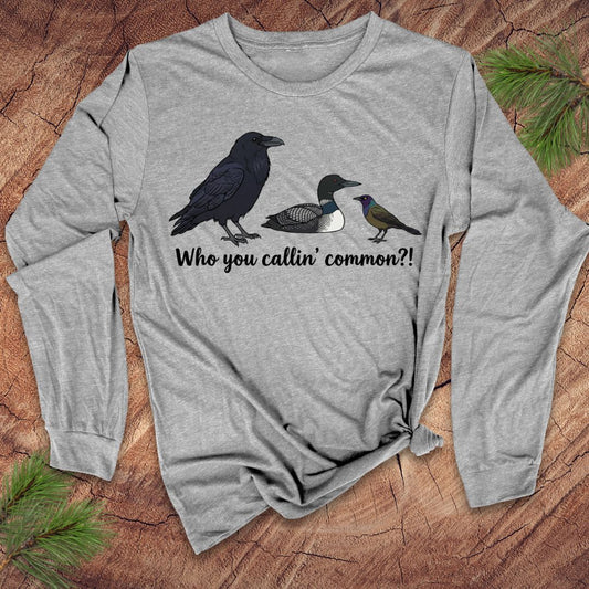 Gray long-sleeve shirt with bird illustrations and text on a wooden surface