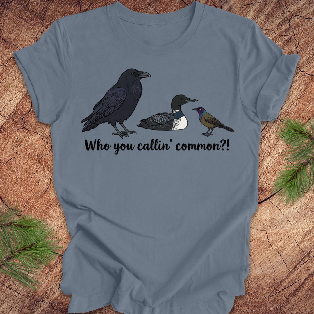 Blue t-shirt with bird illustrations and text on a wooden surface