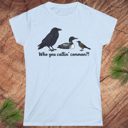 Light blue t-shirt with bird illustrations and text on a wooden surface