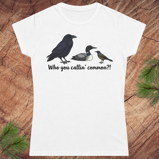 White t-shirt with bird illustrations and text on a wooden surface