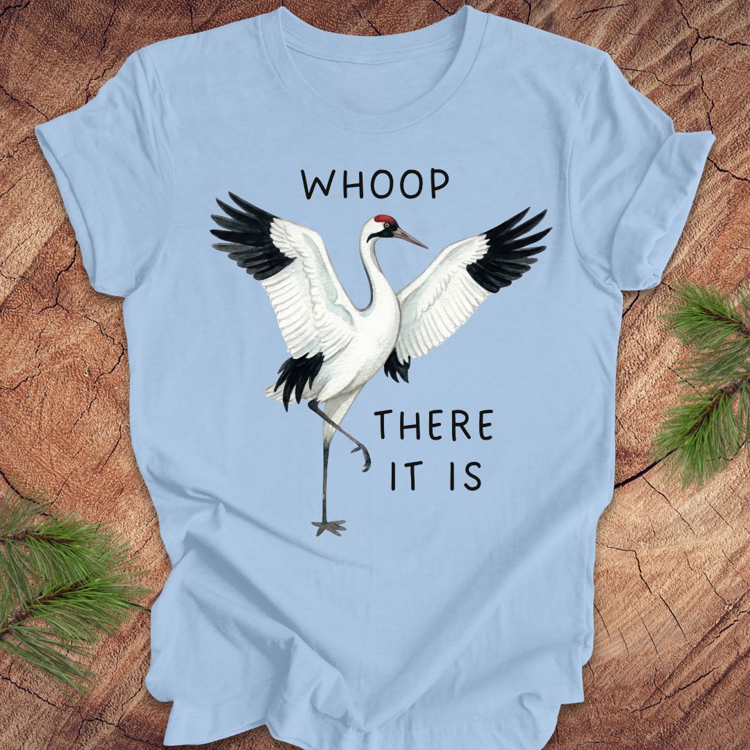 Light blue t-shirt with a crane graphic and text, 'whoop there it is' on a wooden surface
