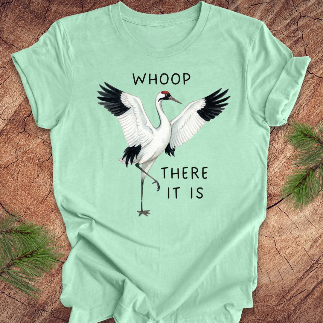 Mint green t-shirt with a crane graphic and text, 'whoop there it is' on a wooden surface