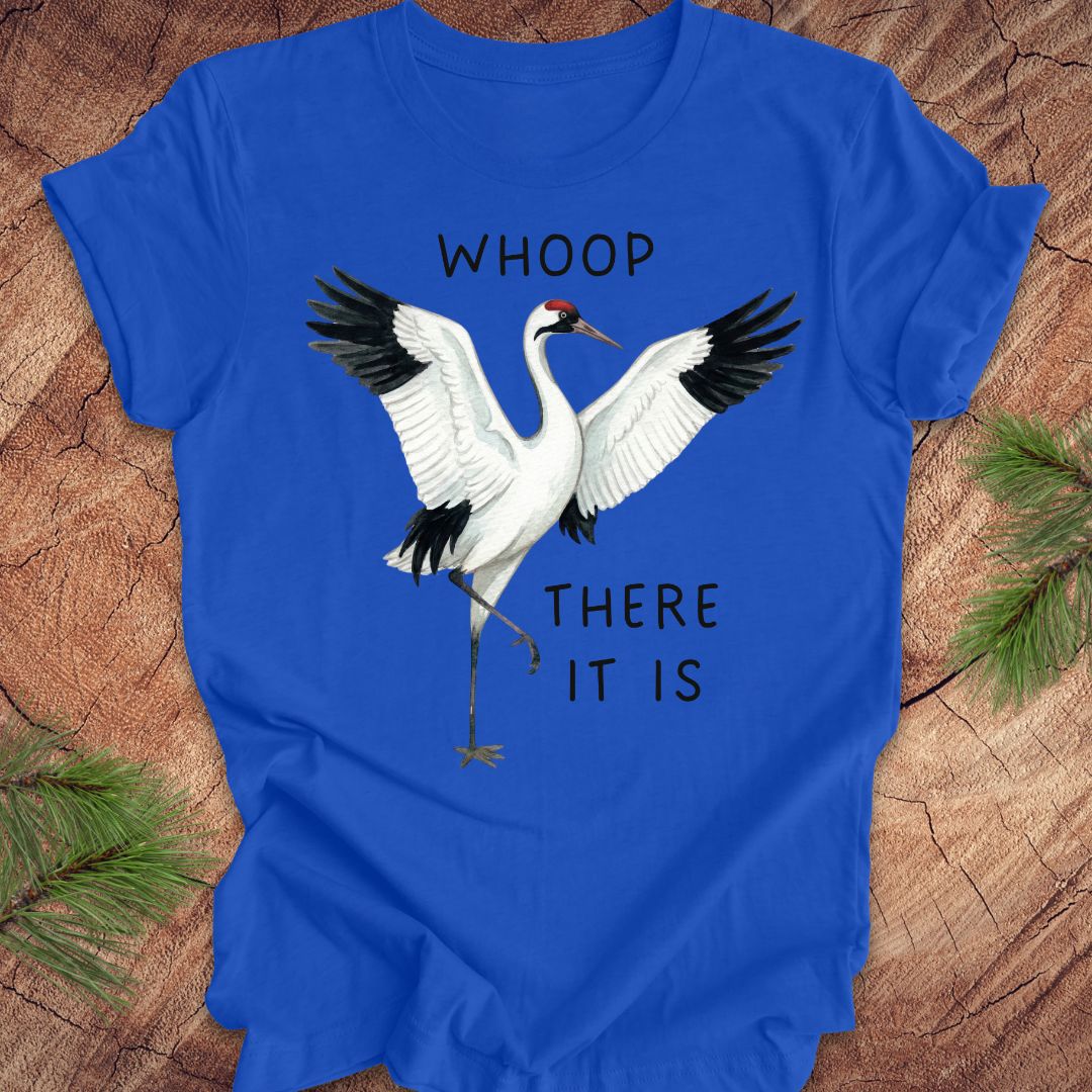 Royal blue t-shirt with a crane graphic and text, 'whoop there it is' on a wooden surface