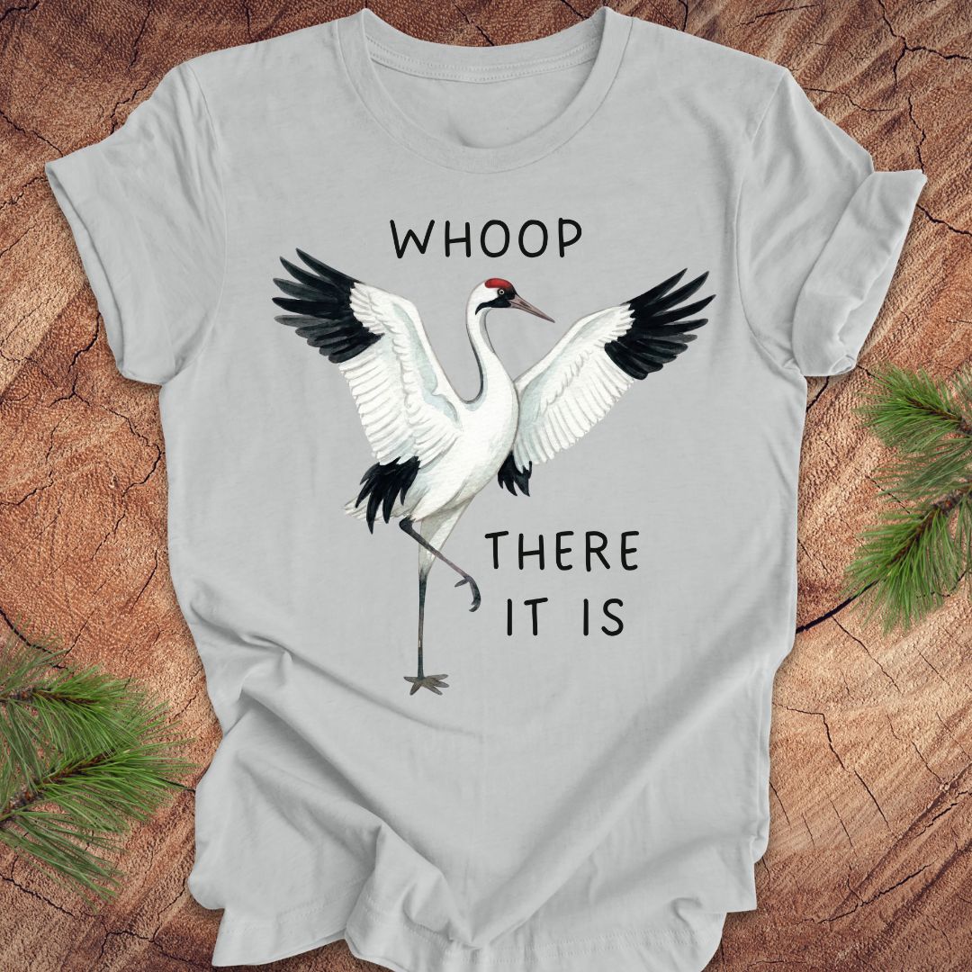 Gray t-shirt with a crane graphic and text, 'whoop there it is' on a wooden surface