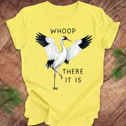 Yellow t-shirt with a crane graphic and text, 'whoop there it is' on a wooden surface