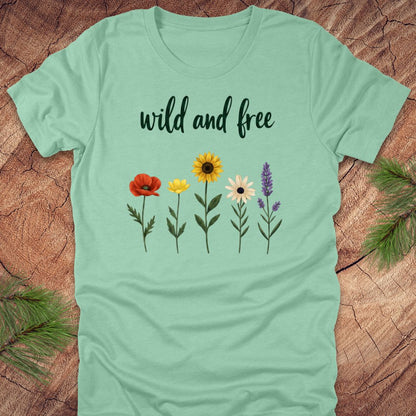 Light green t-shirt with floral designs and 'wild and free' text on a wooden surface.